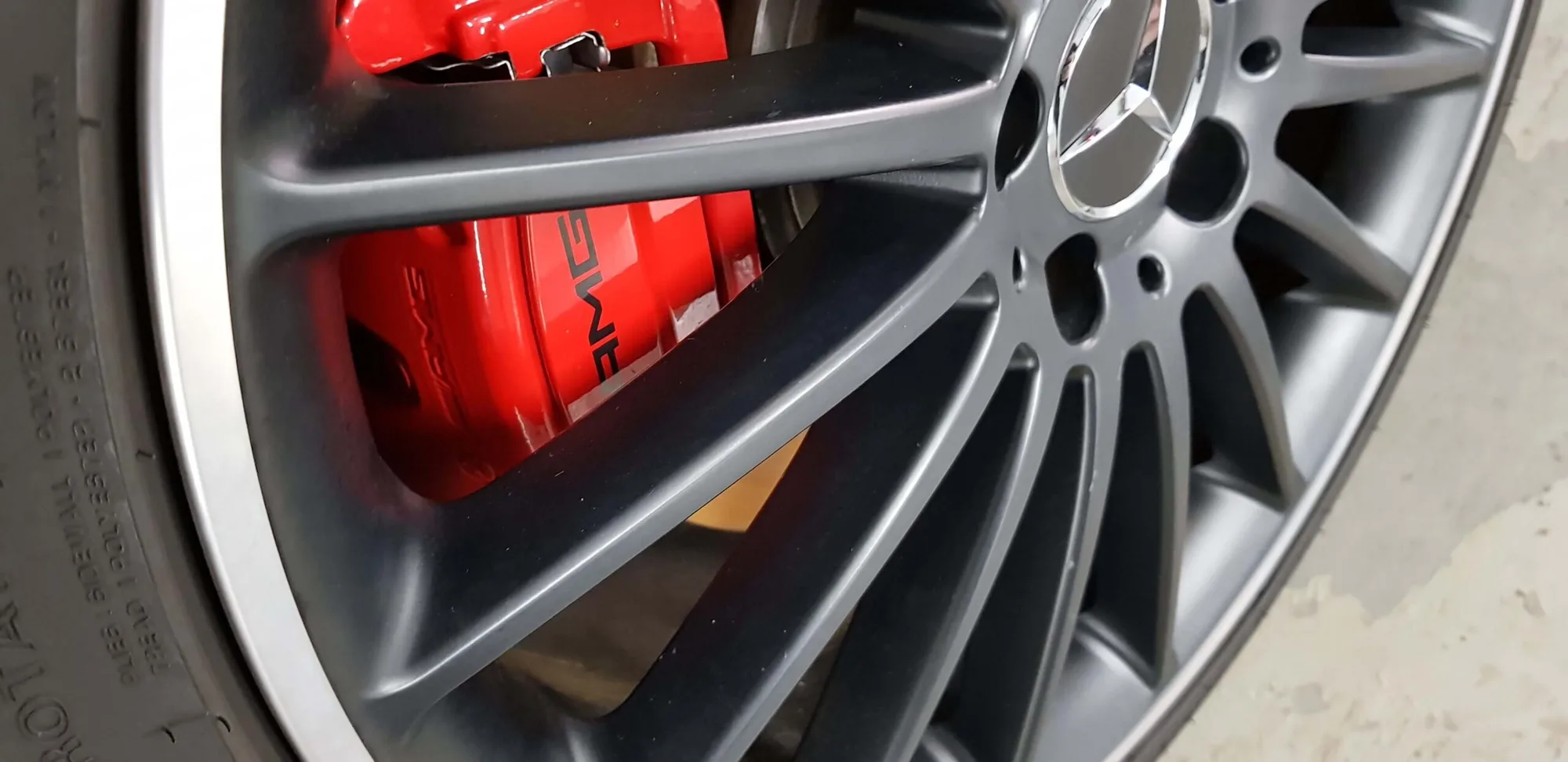 Red AMG brake caliper behind a coated alloy wheel, photographed close up after W750 went on