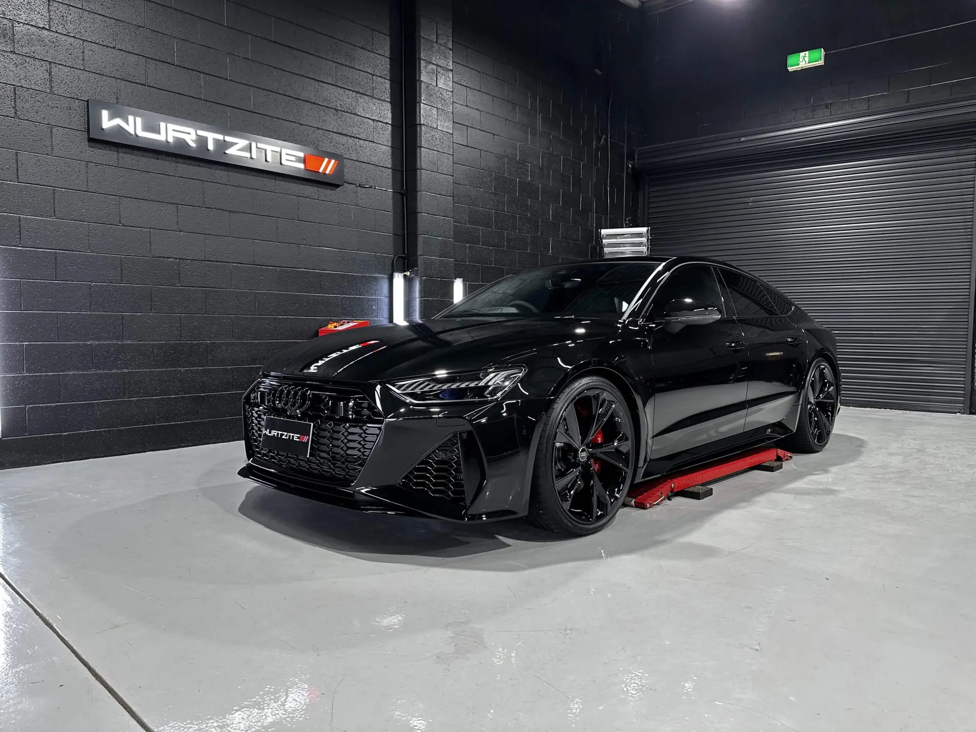Black BMW under workshop lights during a ceramic paint protection application at Ceramicar Adelaide