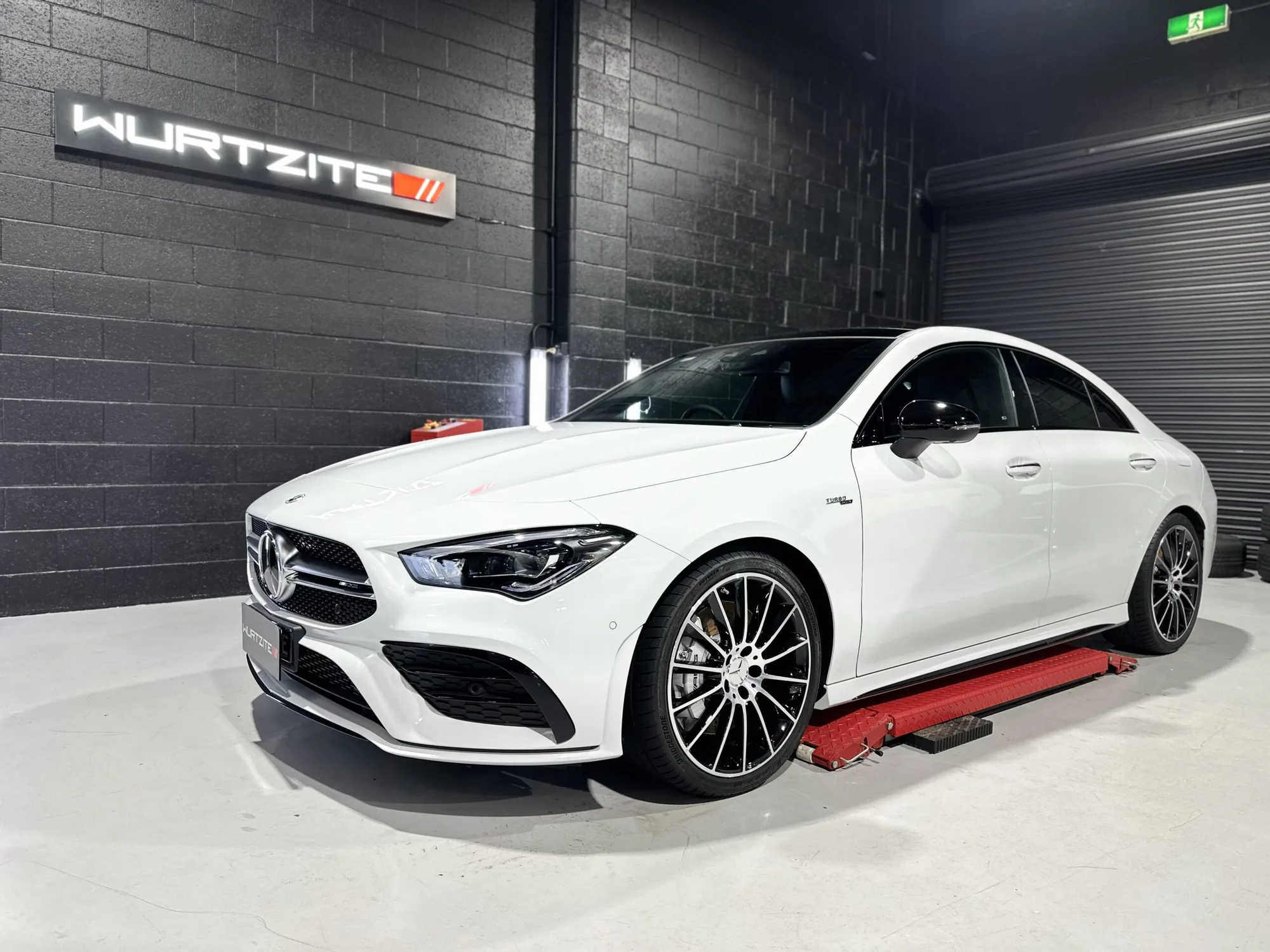 White Mercedes-AMG CLA under the Wurtzite sign in the Ceramicar coating bay