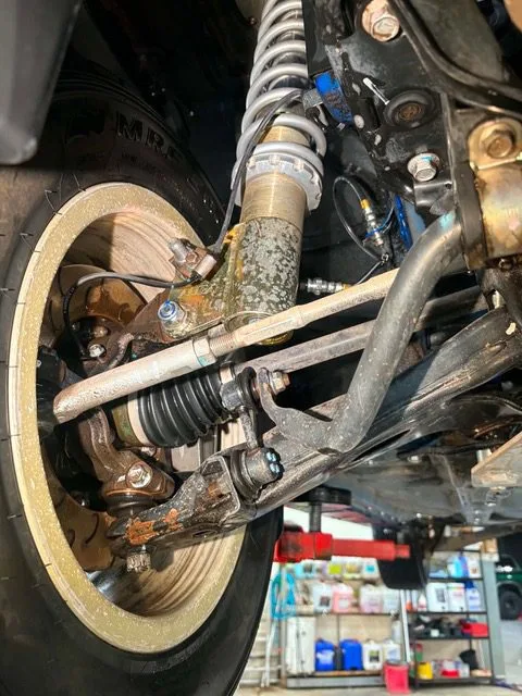Grease and road grime packed around the rear suspension arm and coil spring of a 4x4